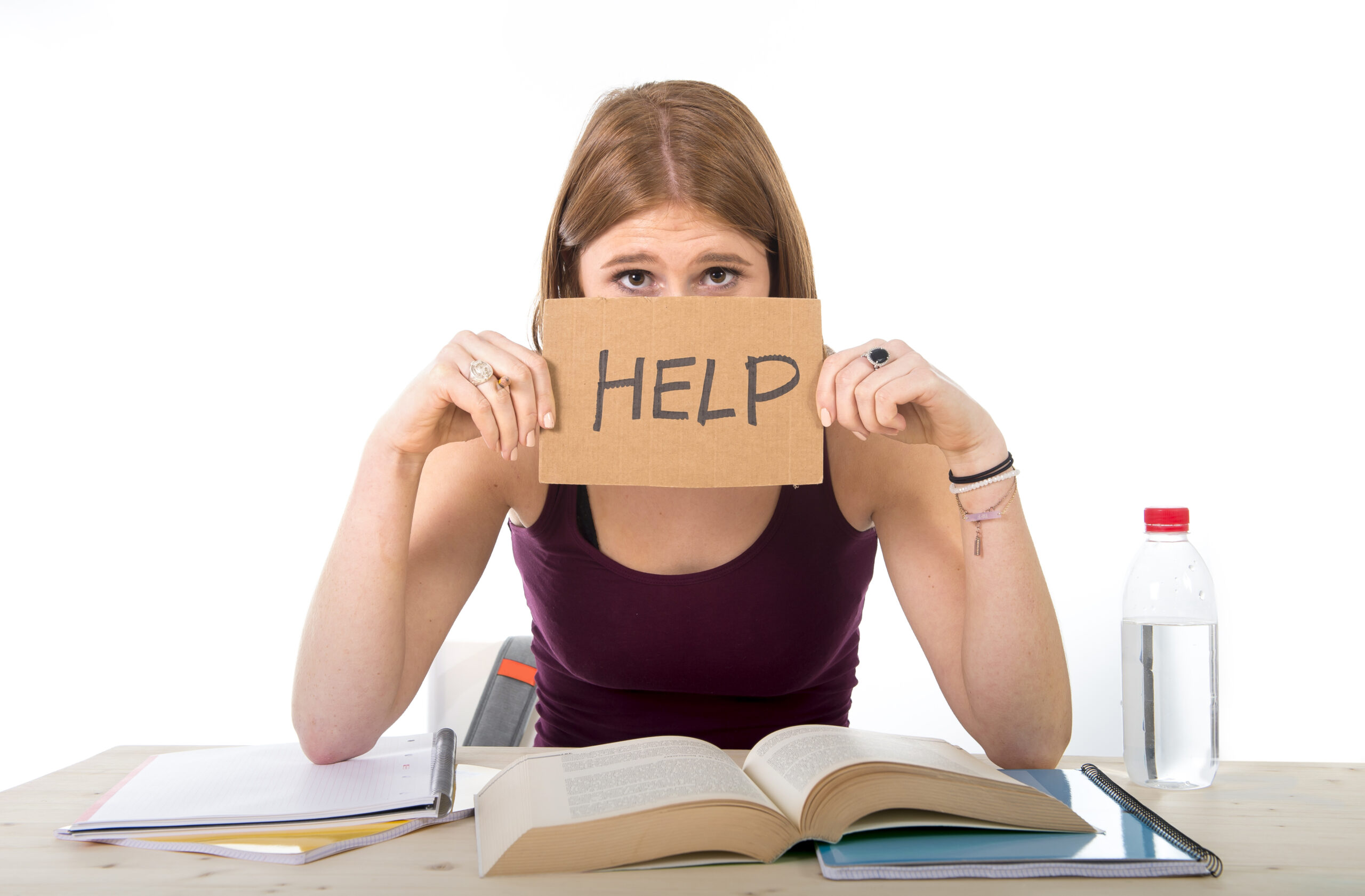 young beautiful college student girl studying for university exam in stress asking for help under test pressure sitting on desk with book in youth education concept