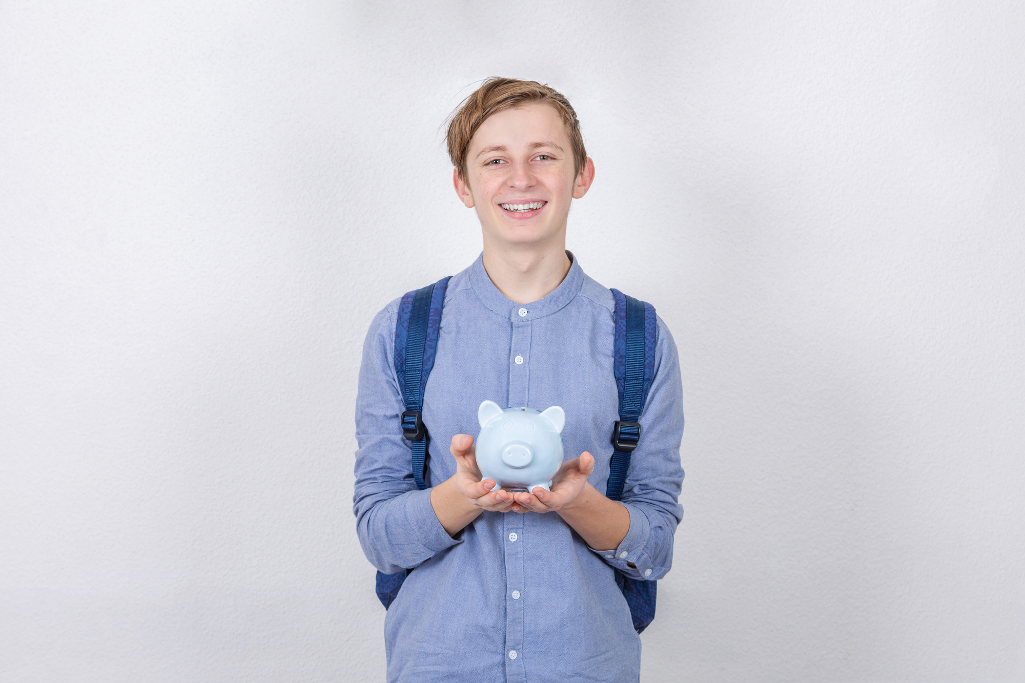 teen boy holding piggy bank