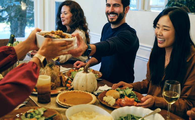 Family sitting around table eating Thanksgiving dinner.