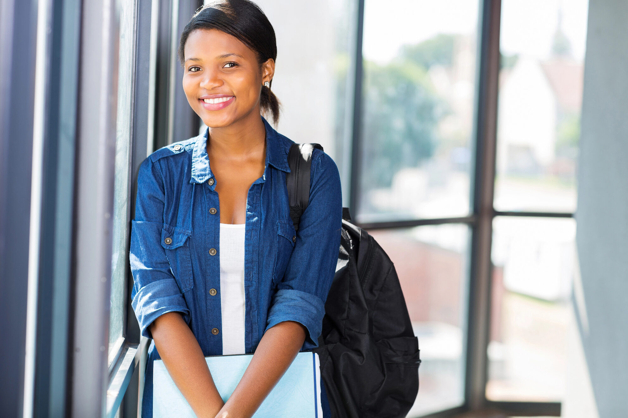 High school girl with backpack and holding books.