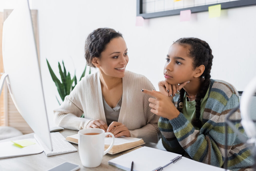 High school girl sitting at a computer with her mother.