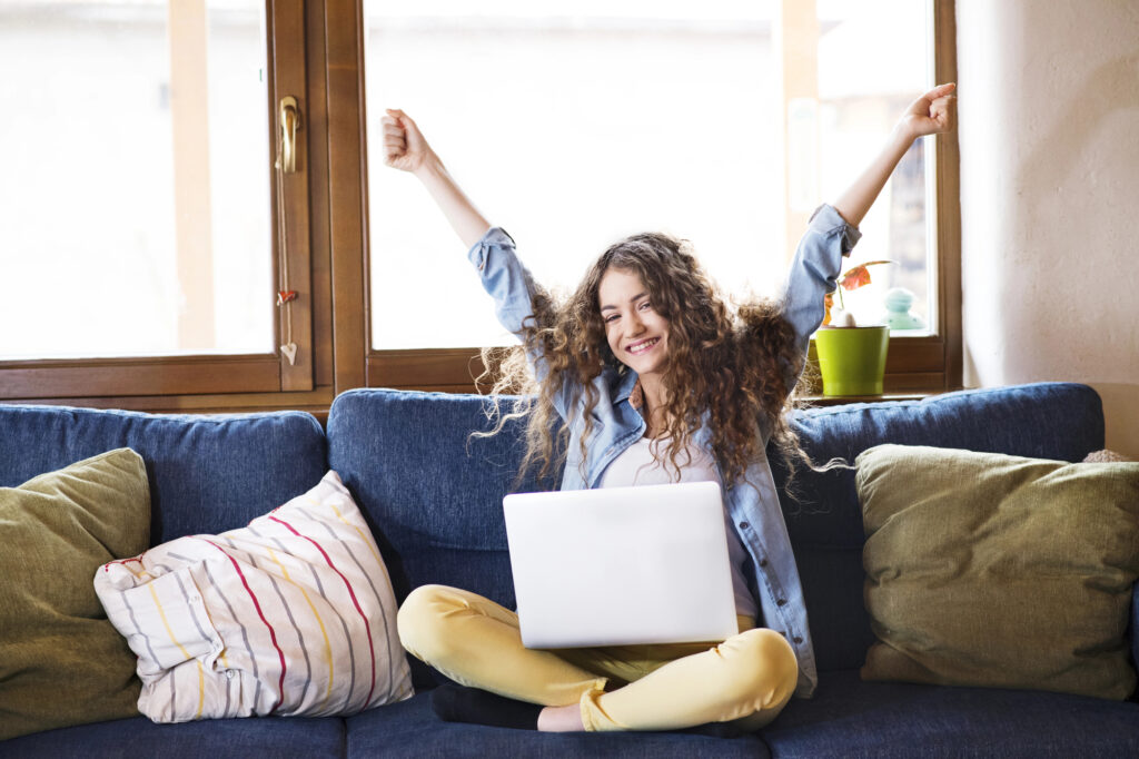 High school girl celebrating while sitting on a couch.