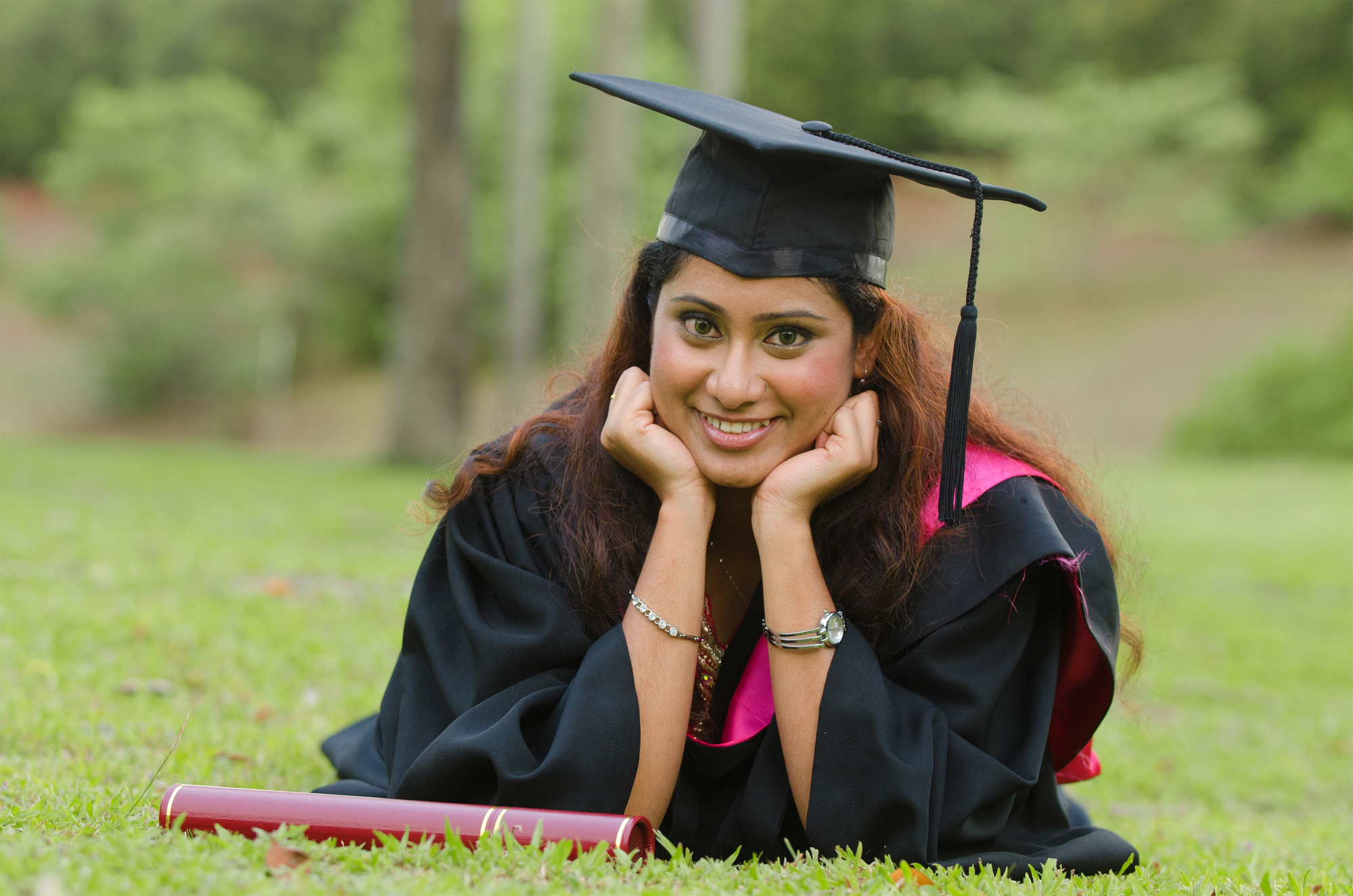 Girl laying on the ground in her graduation hat and gown.