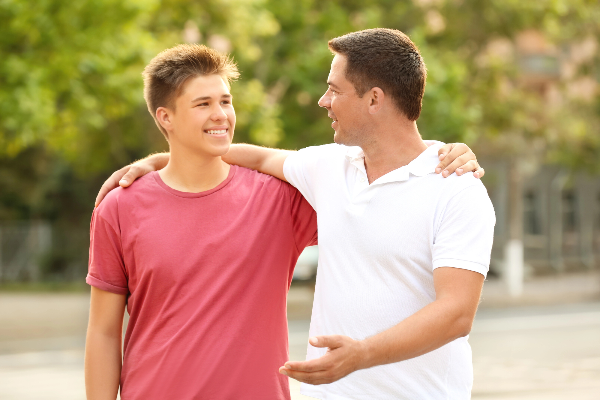 Father and son walking outside having a conversation.