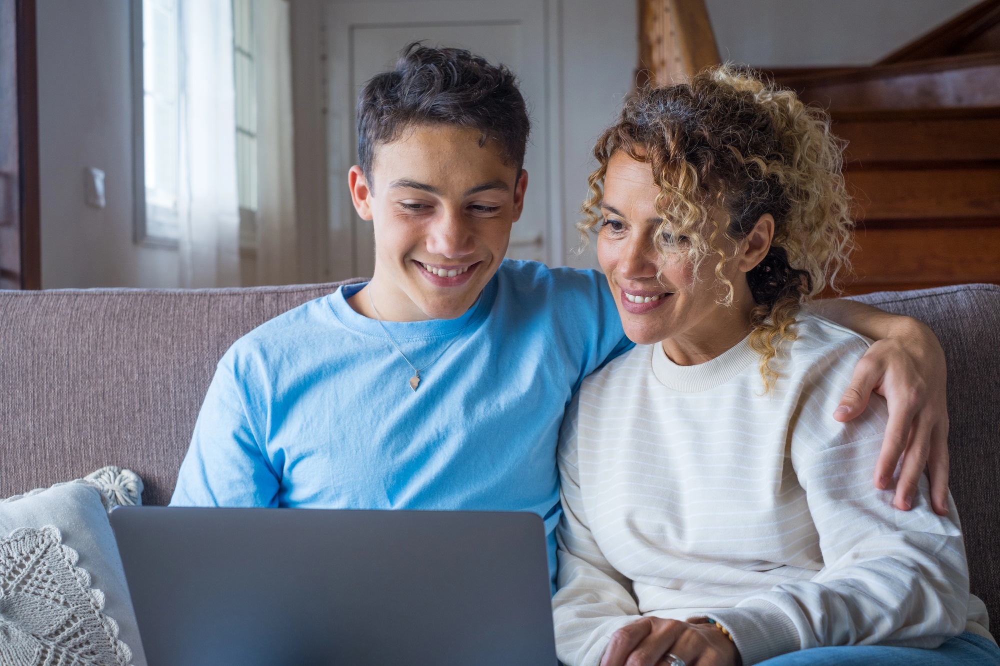 Mom and son sitting on a couch looking at laptop