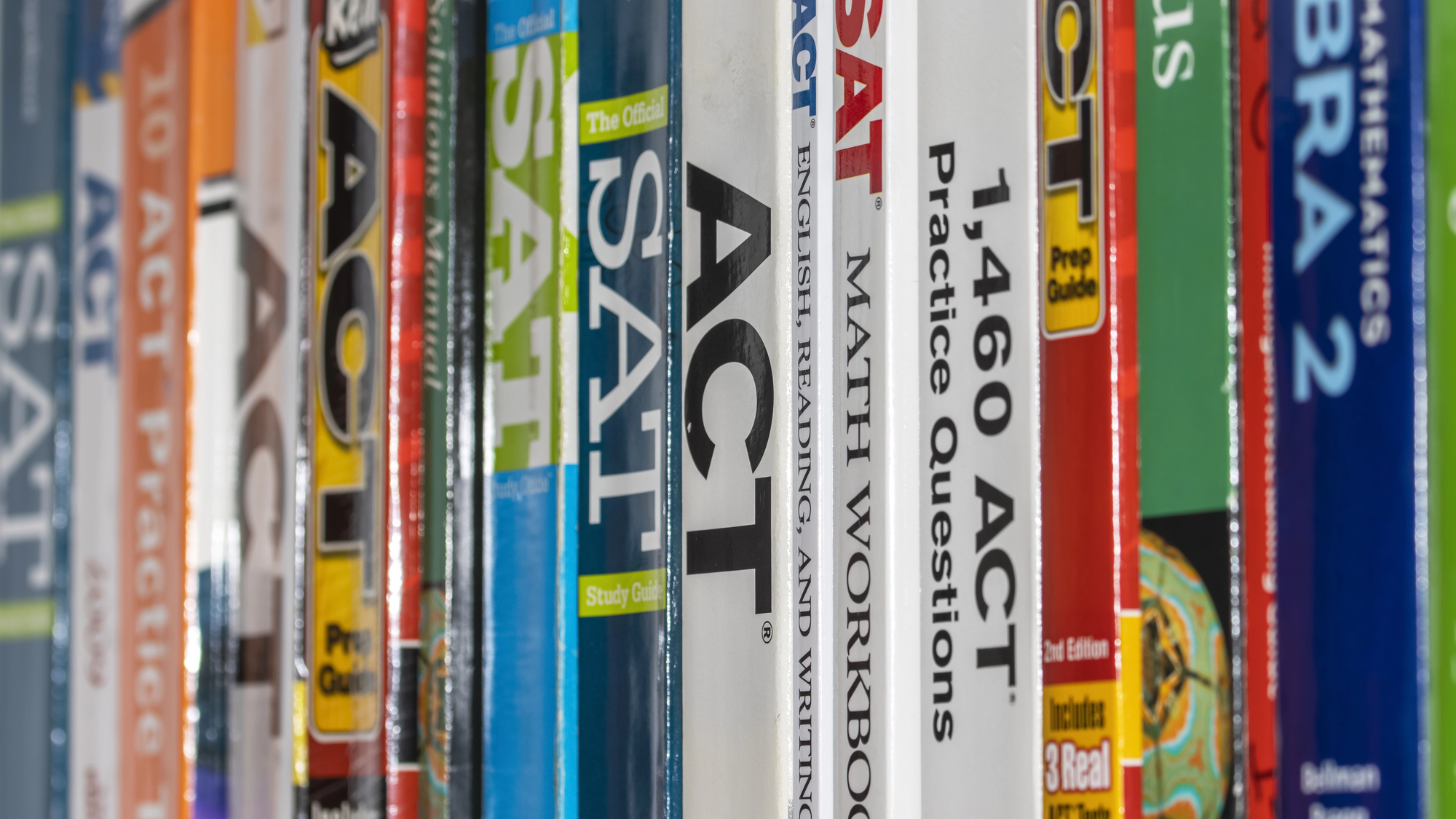 A row of SAT and ACT prep books on a shelf, representing college entrance exam preparation.