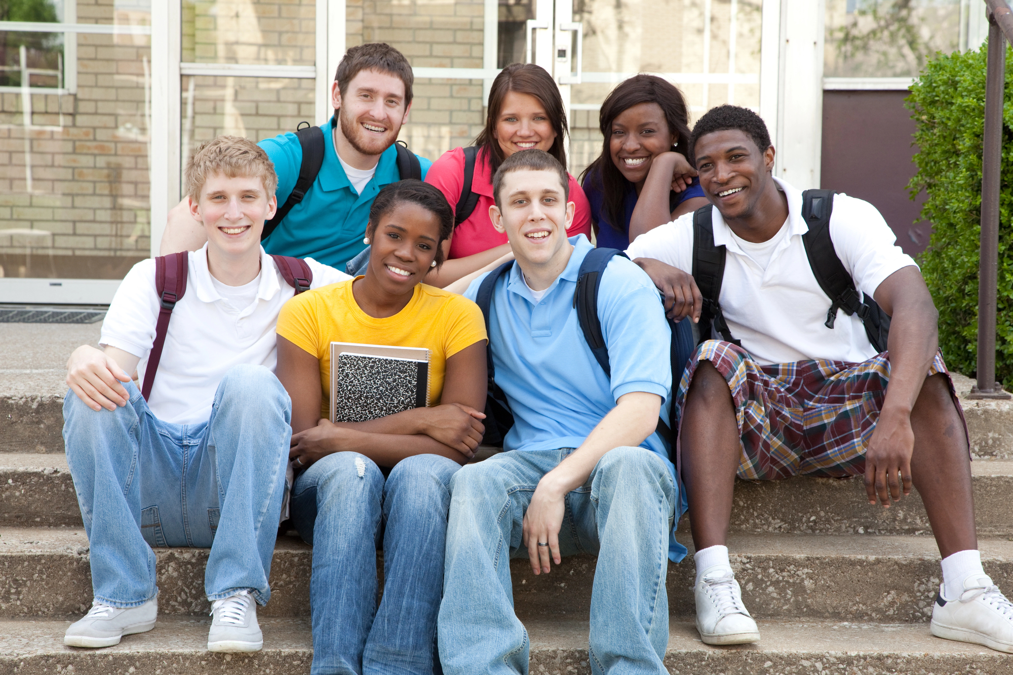 High school juniors sitting on steps with backpacks, preparing for college planning.