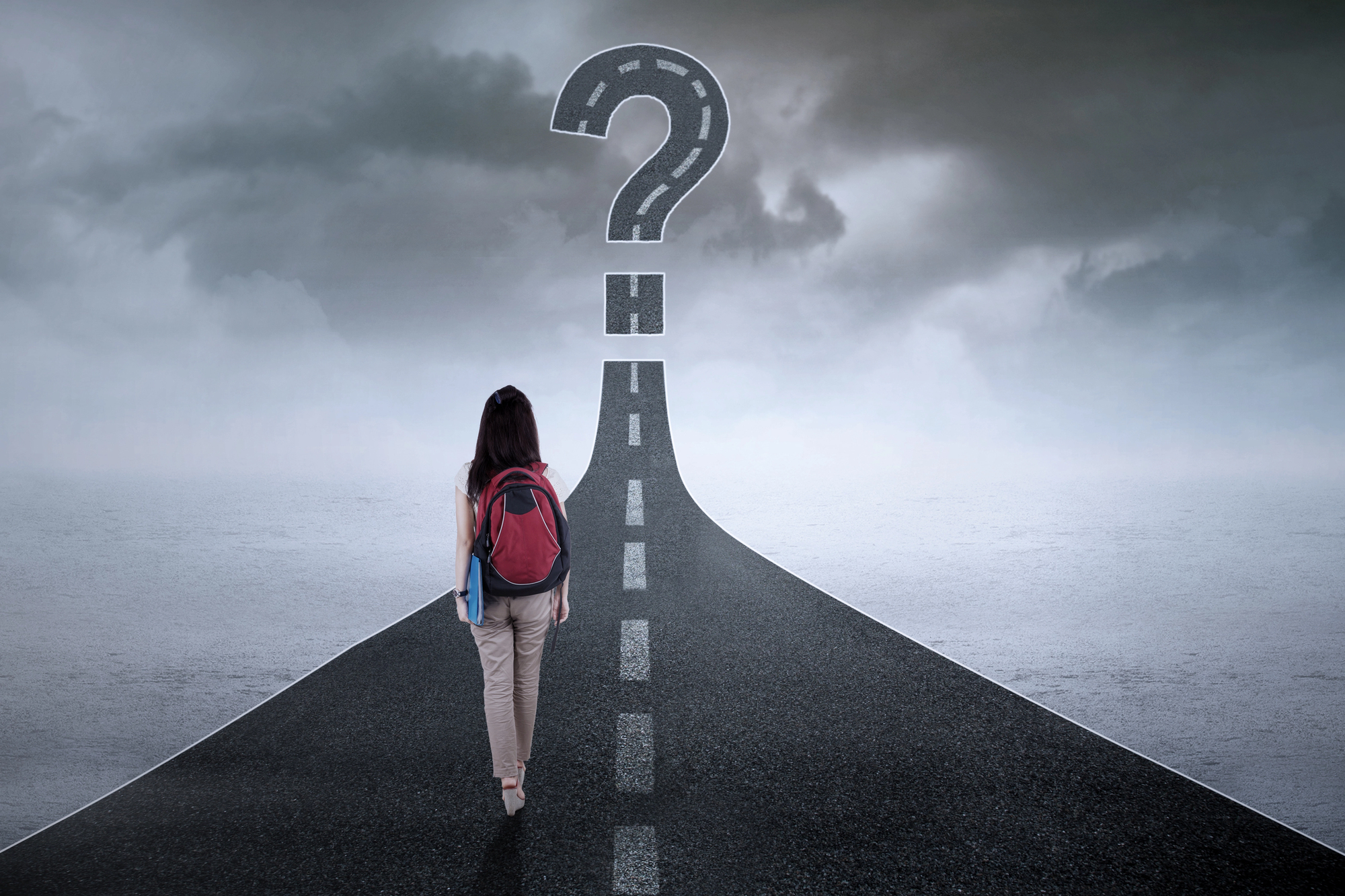 A high school student wearing a backpack walks down a road that turns into a question mark, symbolizing uncertainty about their future path.