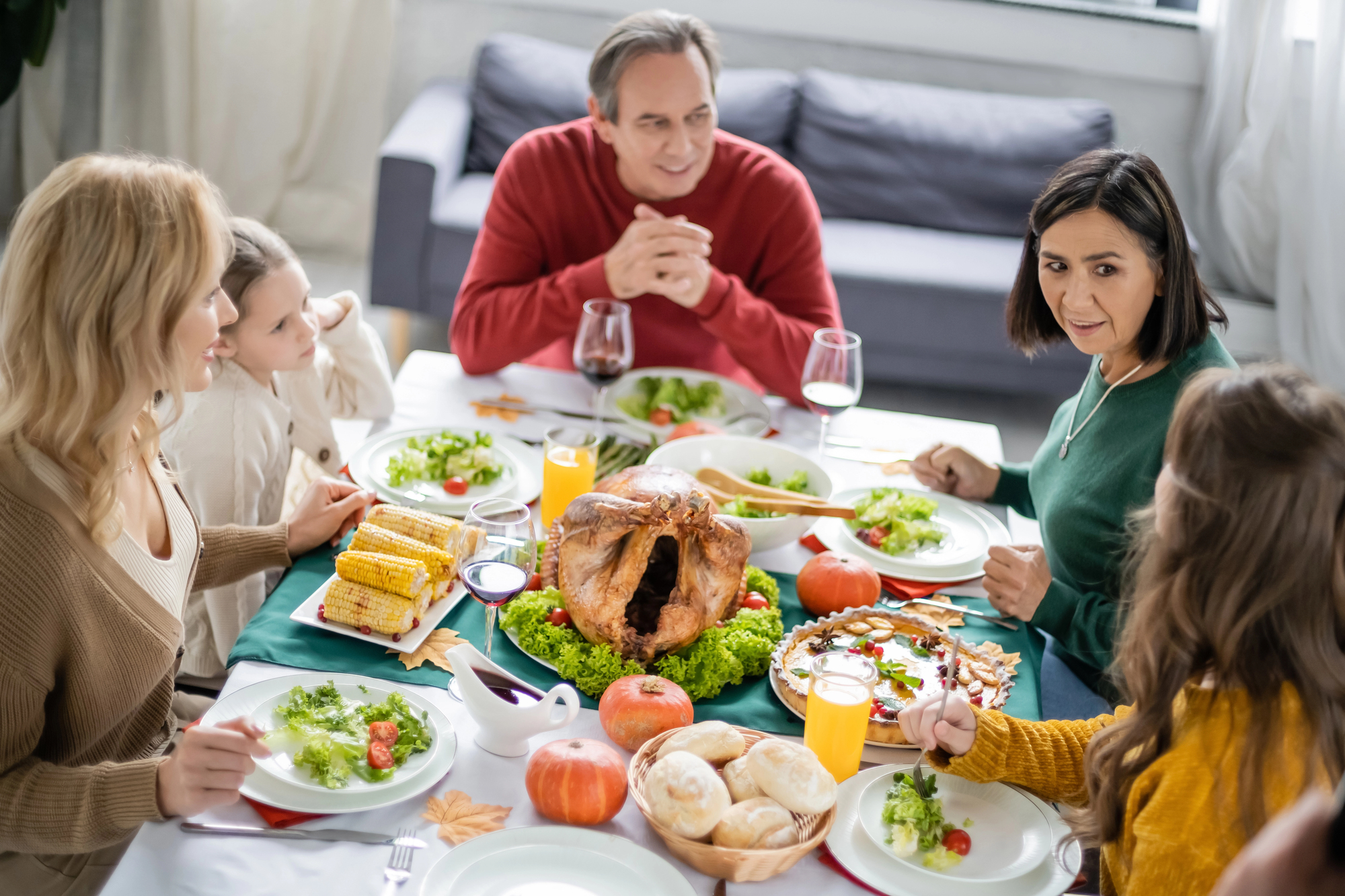 A family gathered around a Thanksgiving dinner table, talking and sharing a meal, creating a warm and connected atmosphere.