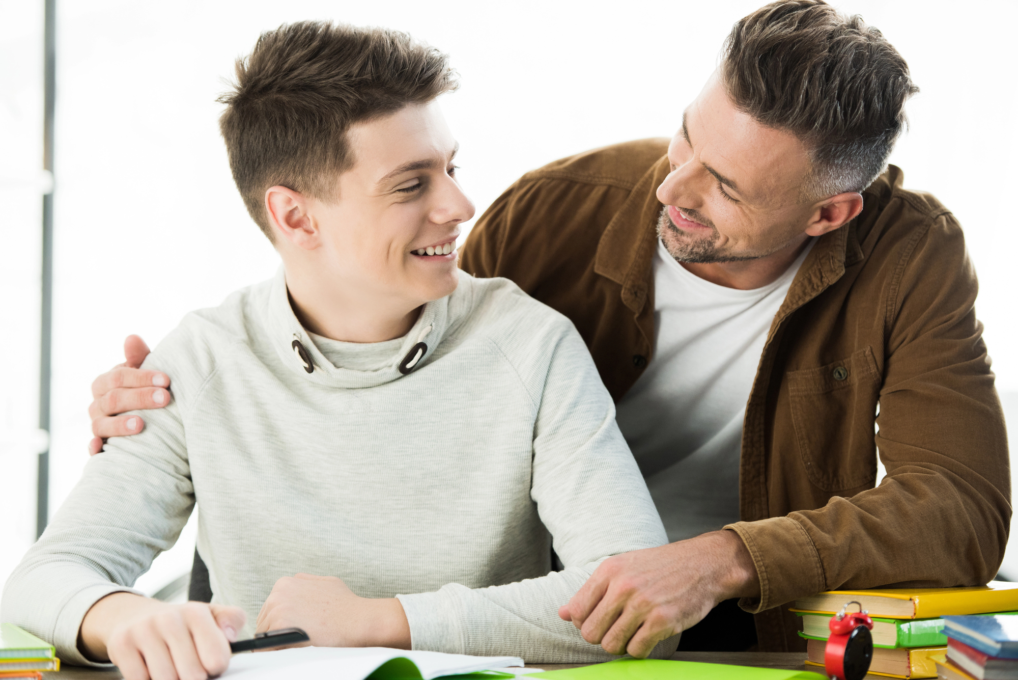 Father having a supportive conversation with his teenage son about school and future plans at a table.