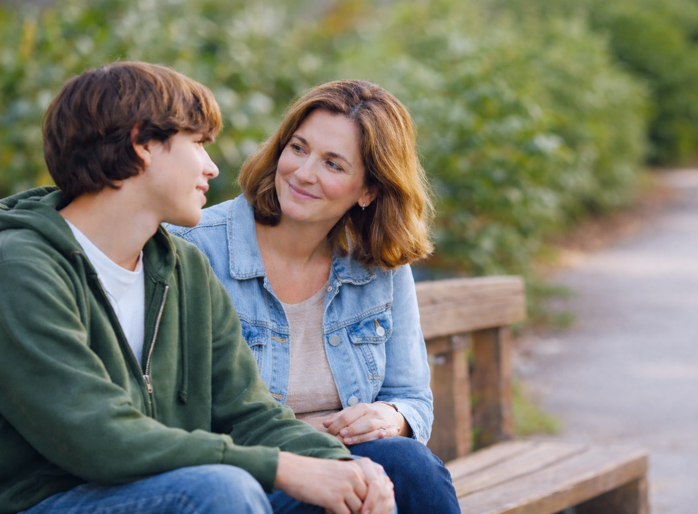 Parent and teen sitting side-by-side on a bench having a calm conversation about the teen’s future