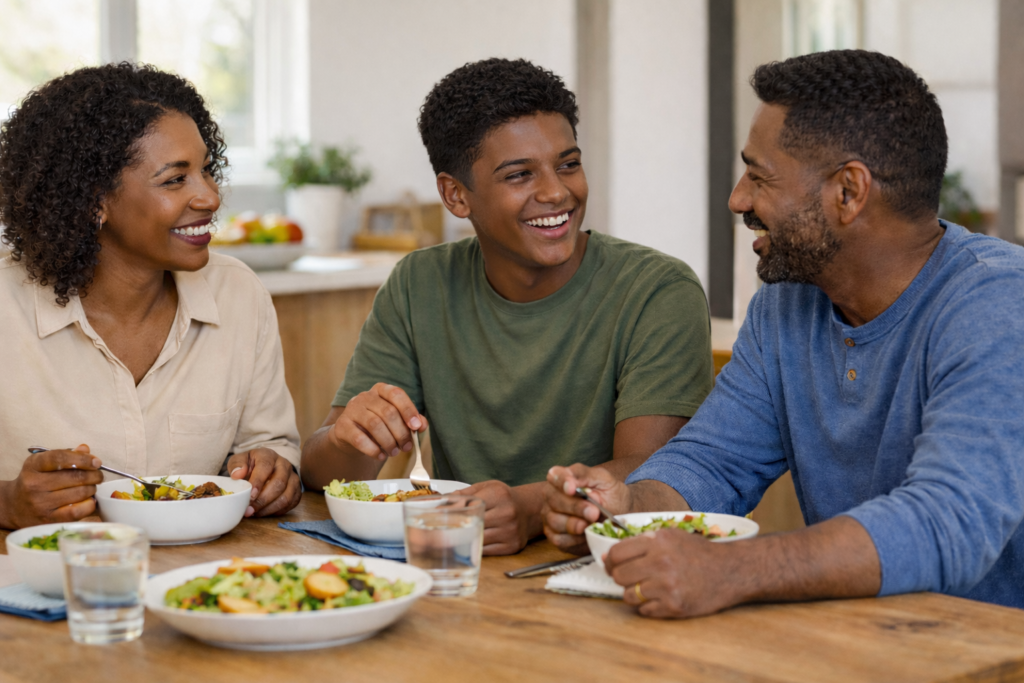 Teen and parents eating dinner at table.