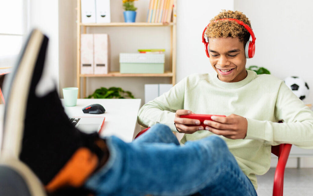 teen boy sitting at desk looking at cell phone