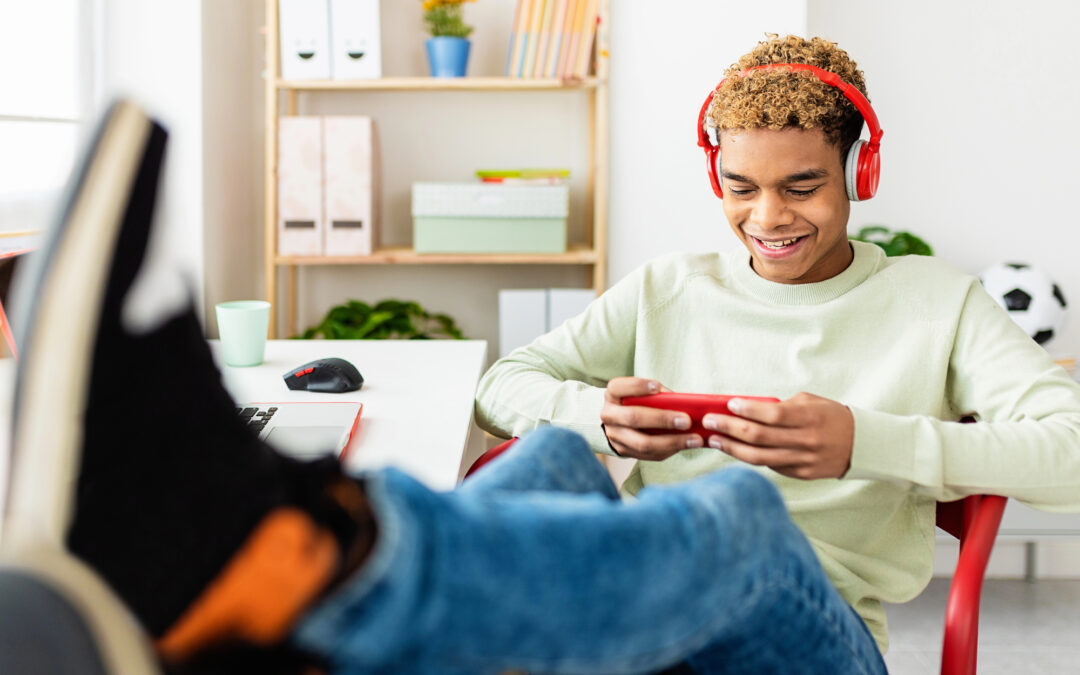 teen boy sitting at desk looking at cell phone
